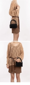 Dettaglio di borsa fatta a mano con perline nere abbinata a top in maglia color kaki