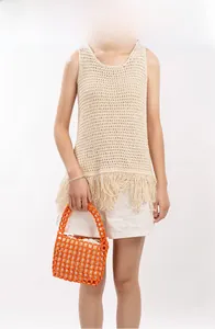 Close-up of beige crochet knit vest with long fringes and orange beaded handbag detail