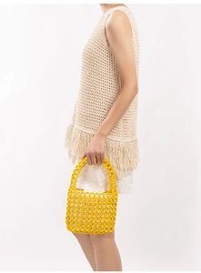Detail of yellow wooden beaded handbag with bohemian crochet vest and fringe