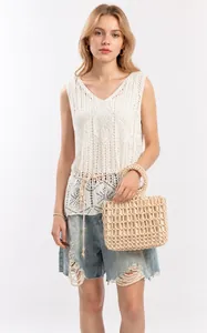 Detail of a handmade cream beaded tote bag paired with a crochet top and denim shorts