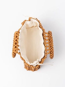Handmade woven wood bead handbag with a beige canvas drawstring pouch for travel