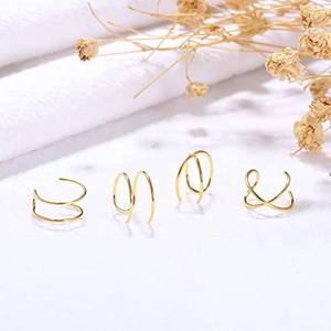Detail view of four gold-plated minimalist ear cuffs on a clean aesthetic background