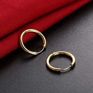 Polished minimalist gold hoop earrings set against luxury red and black fabric backdrop