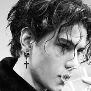 Boucles d'oreilles créoles punk en noir mat avec pendentif croix sur un modèle