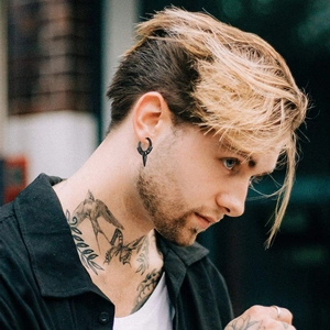 Close-up of a man wearing a black punk hoop earring with a sharp spike pendant detail