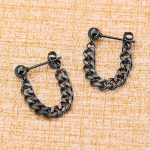 Détail de boucles d'oreilles noires en métal avec un pendentif en chaîne gourmette