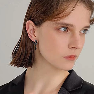 Close-up of black matte lightning bolt charm hoop earring worn by a model