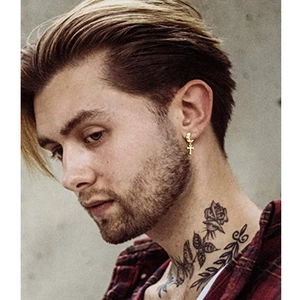 Detail of a gold-plated moon earring with a long cross pendant worn on a model