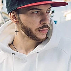 Close-up of black cross dangle earrings with chains worn by a male model in street style