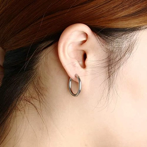 Classic silver polished hoop earrings for women worn by a model in a minimalist style