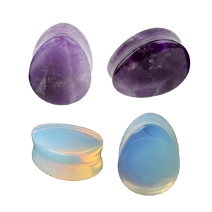 Macro shot of polished teardrop stone ear plugs in amethyst and opalite material