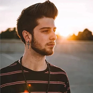 Boucles d'oreilles croix noir mat pour hommes portées par un mannequin en ville