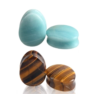 Macro shot of teardrop ear plugs showing natural blue stone and tiger eye textures