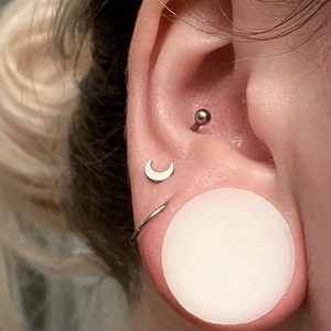Close-up of silicone ear gauges and moon studs on ear for body piercing styles
