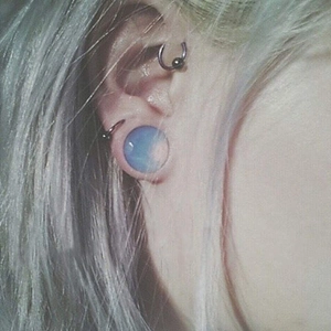 Blue opal stone ear plug and silver metal CBR rings set worn on human ear lobe