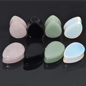 Macro view of teardrop stone ear plugs in rose quartz opal and obsidian on black surface