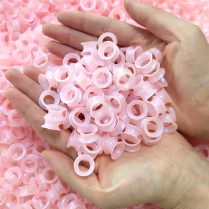 Dettaglio di dilatatori auricolari in silicone rosa traslucido tenuti nelle mani