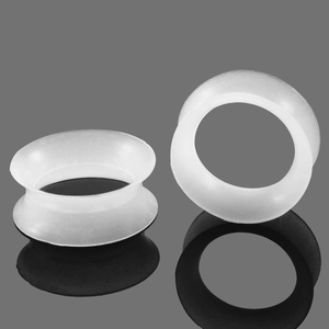 Dettaglio dei tunnel per orecchie in silicone bianco su una superficie nera riflettente
