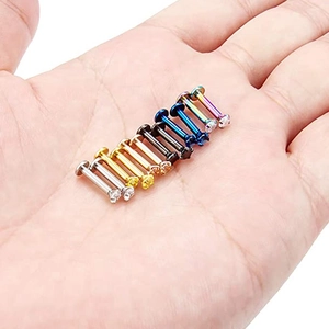 Set di sei piercing labret 16G colorati con zirconi tenuti in mano per la scala
