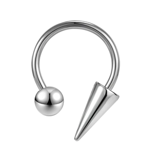 Close-up of polished stainless steel horseshoe ring with spike and ball ends piercing