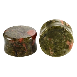Detail of flared natural green stone ear plugs with organic orange speckles on white background
