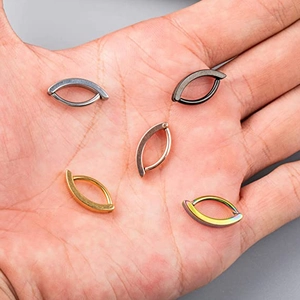 Five pieces of polished stainless steel belly rings in various colors held in hand