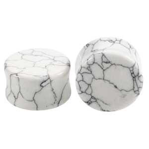 Macro detail of white turquoise saddle ear plugs with natural black marble texture
