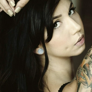 Polished light blue stone ear plugs for body piercing shown on model earlobe