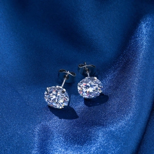 Makroaufnahme von 4-Krallen-Zirkonia-Ohrsteckern auf blauem Seidenstoff mit Brillanz