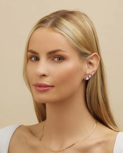 Model wearing gold curb chain necklace and graduated white opal stud earrings in 4-prong setting