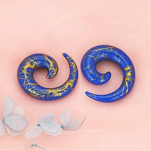 Blue acrylic spiral ear gauges with gold splatter detail on soft pink textured background