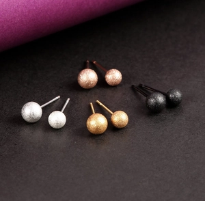 Macro shot of matte glitter ball stud earrings in silver, gold, rose gold and black