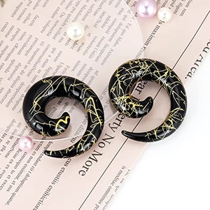 Detail of black acrylic spiral ear gauges with golden marble texture on a magazine