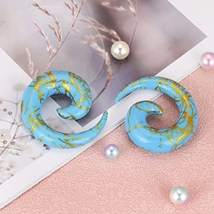 Macro detail of sky blue acrylic spiral ear gauges with elegant gold foil marbling texture