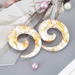 Detailed macro shot of white acrylic spiral ear tapers with golden paint splatter patterns
