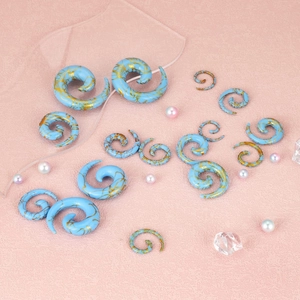 Blue marble acrylic spiral ear gauged plug set with gold swirl patterns on pink background