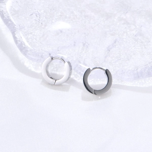 Detailed close-up of two pairs of minimalist silver hoop earrings with enamel inlay on silk