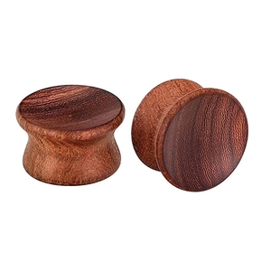 Dettaglio di dilatatori auricolari in legno naturale lucidato con venature rosso scuro