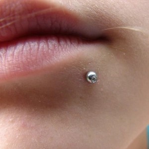 Lippenpiercing aus Edelstahl mit weißem Kristallbesatz in der Nahaufnahme am Mund
