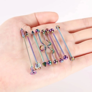Makroansicht von acht regenbogenfarbenen Industrial-Piercings aus Edelstahl auf einer Hand