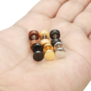 Gros plan de neuf paires de boucles d'oreilles rondes en bois et acier dans une main