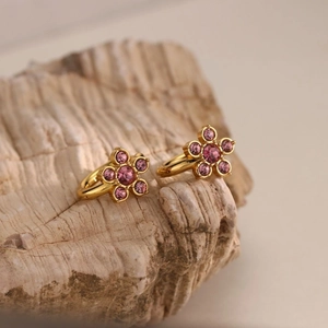 Λεπτομέρεια από σκουλαρίκια λουλούδια 18K χρυσού με ροζ κρύσταλλα σε πέτρινη βάση