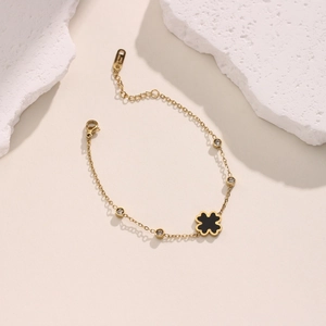 Detail of 18K gold plated stainless steel bracelet with black clover and crystals