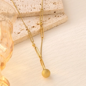 Close-up of 18K gold plated necklace with matte ball pendant on stone display