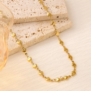 Close-up of 18K gold plated heart chain link necklace on a textured stone display