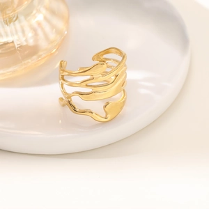 Detail of 18K gold-plated irregular hollow ring with liquid metal texture on a white plate