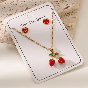 Détail de la parure de bijoux en acier doré 18 carats avec pendentifs fraises rouges