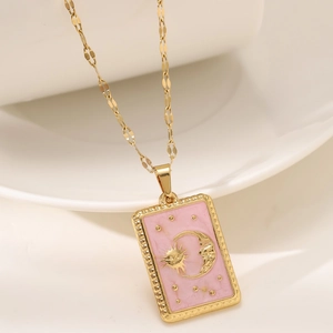 Macro detail of sun and moon relief on pink enamel tarot pendant with gold chain