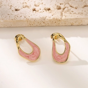 Dettaglio macro di orecchini irregolari in smalto rosa marmorizzato e metallo dorato