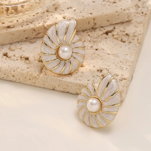 Elegant conch shell stud earrings with pearls on a textured travertine stone background